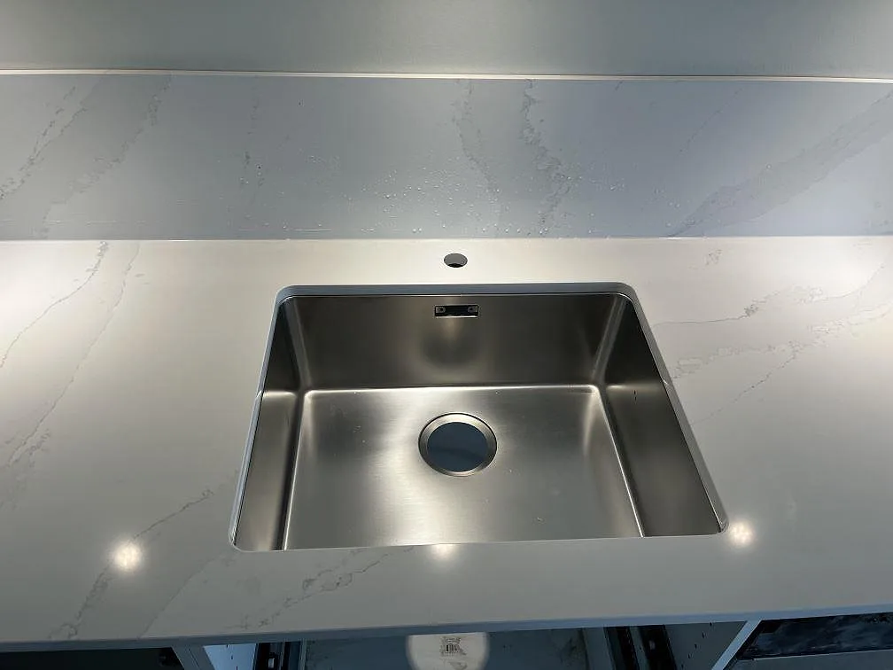 Infälld Siemens induktionshäll i en polerad köksbänkskiva av Silestone Eternal Calacatta Gold med matchande stänkskydd i Malmö.