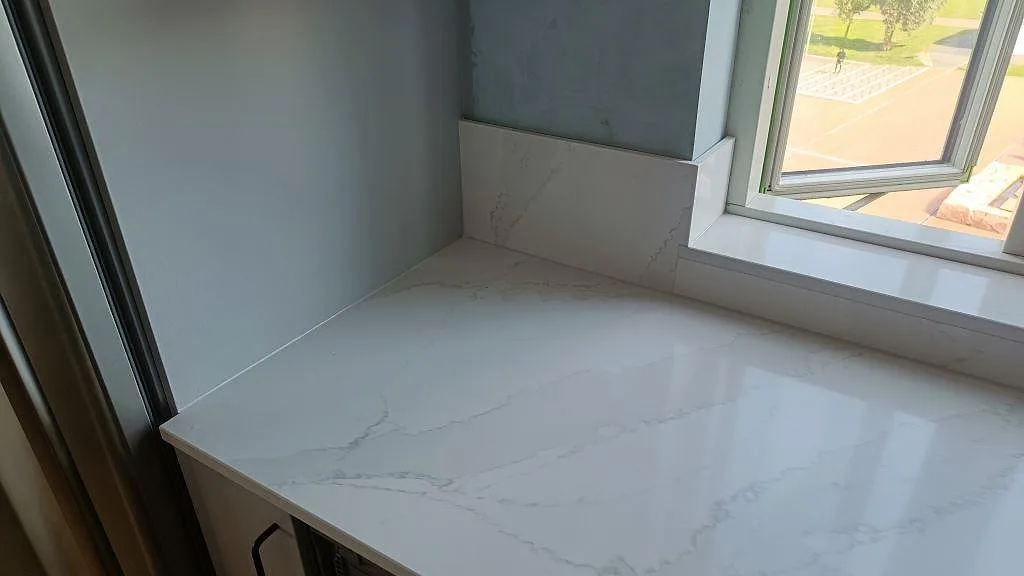 Polerad Silestone Eternal Calacatta Gold som köksbänkskiva vid fönster, med ljus ådring och stänkskydd i Malmö.