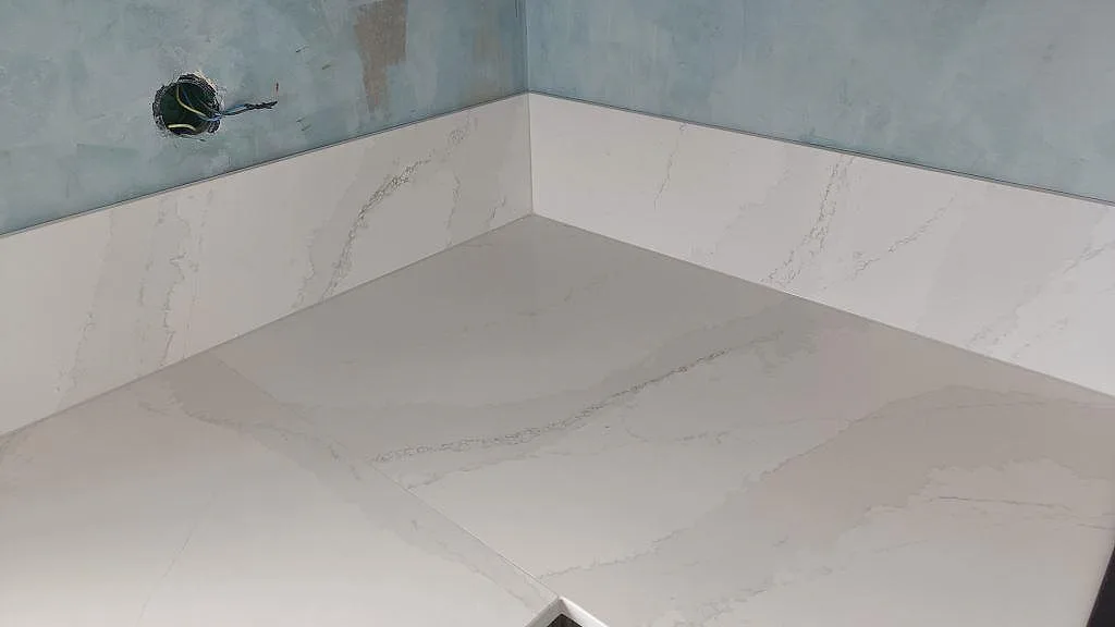Detalj av hörn och stänkskydd i polerad Silestone Eternal Calacatta Gold med mjuk grå ådring i Malmö.