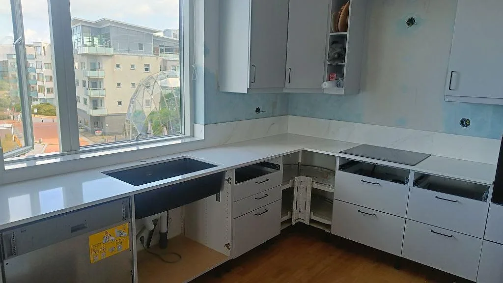 Köksbänkskiva i vit Silestone Eternal Calacatta Gold, polerad komposit, med mörk underlimmad diskho och svart häll i ett kök i Malmö.