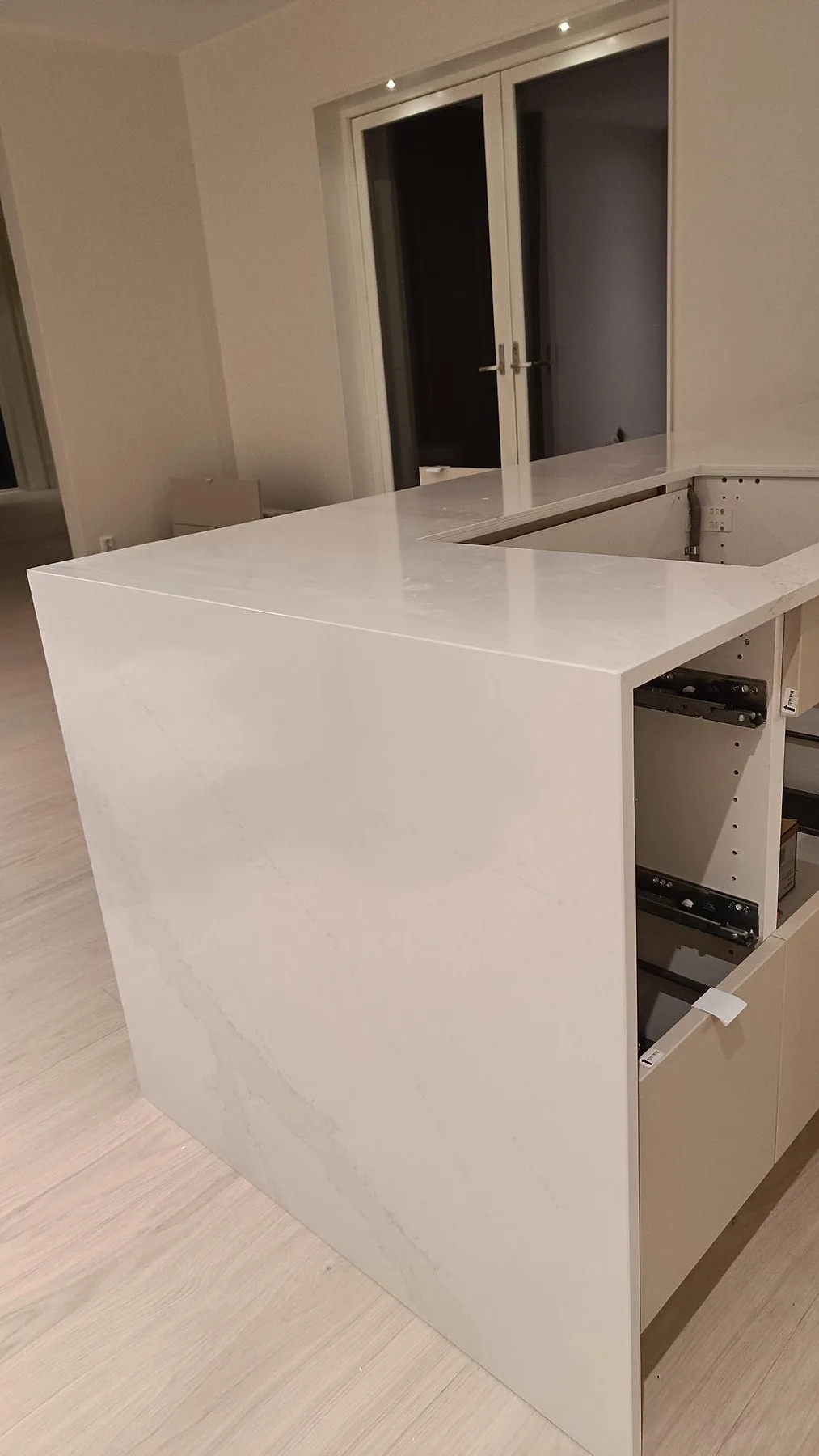 Närbild på polerad Silestone Eternal Calacatta Gold som bänkskiva med lodrät sidoklädsel och mjuk ådring i ett kök i Onsala.