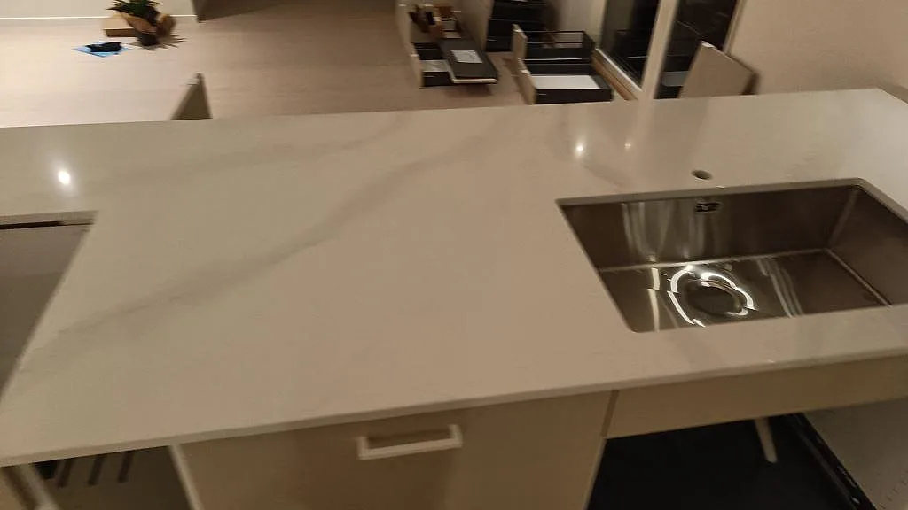 Detalj av polerad Silestone Eternal Calacatta Gold med rostfri diskho, blandarhål och köksbänk i Onsala.