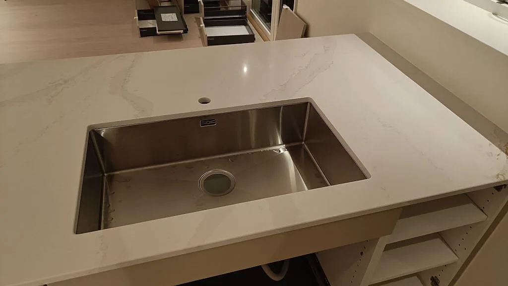 Polerad köksbänkskiva i Silestone Eternal Calacatta Gold med rostfri diskho och ljus ådring i Onsala.