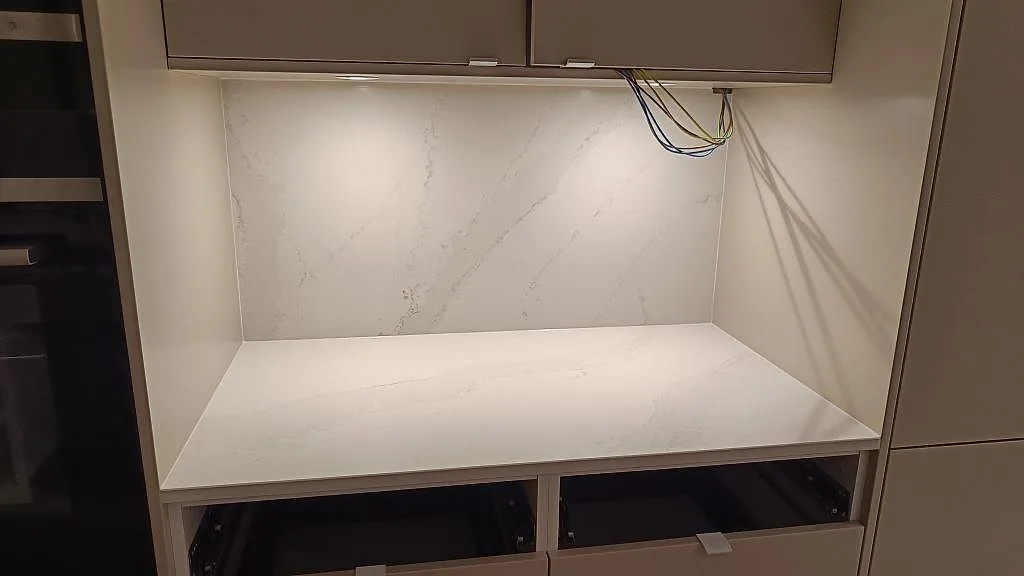 Polerad Silestone Eternal Calacatta Gold som bänkskiva och stänkvägg mellan under- och överskåp i ett kök i Onsala.
