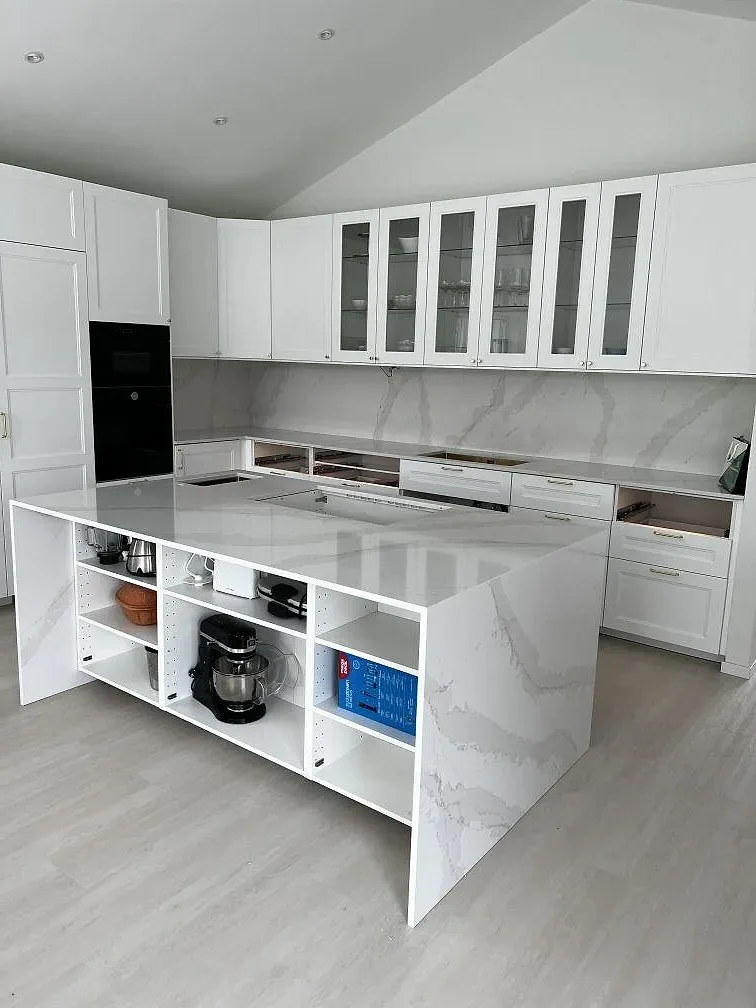 Polerad Silestone Eternal Calacatta Gold på köksö och bakre bänkskiva med svart häll i Simrishamn.