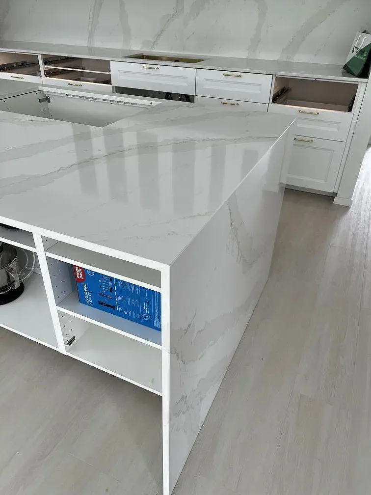 Detalj av polerad Silestone Eternal Calacatta Gold på köksö med grå ådring och vit köksinredning i Simrishamn.