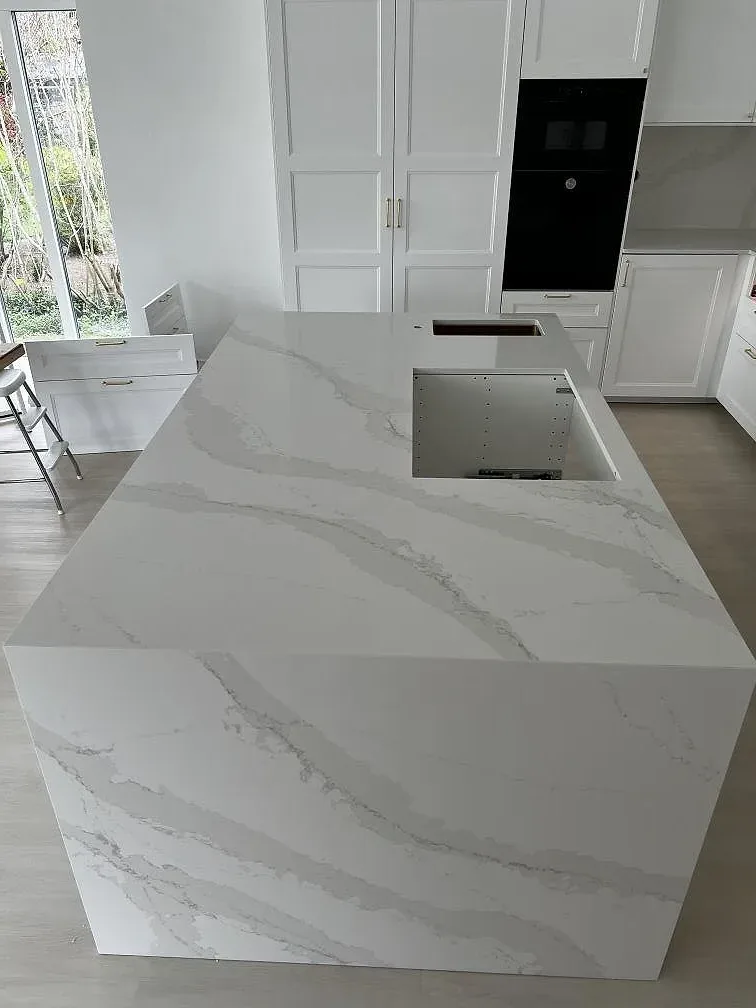Närbild på köksö i polerad Silestone Eternal Calacatta Gold med Calacatta-ådring och vattenfallssida i Simrishamn.