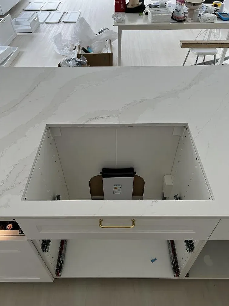 Sidovy av köksö i polerad Silestone Eternal Calacatta Gold med öppna stommar under montering i Simrishamn.