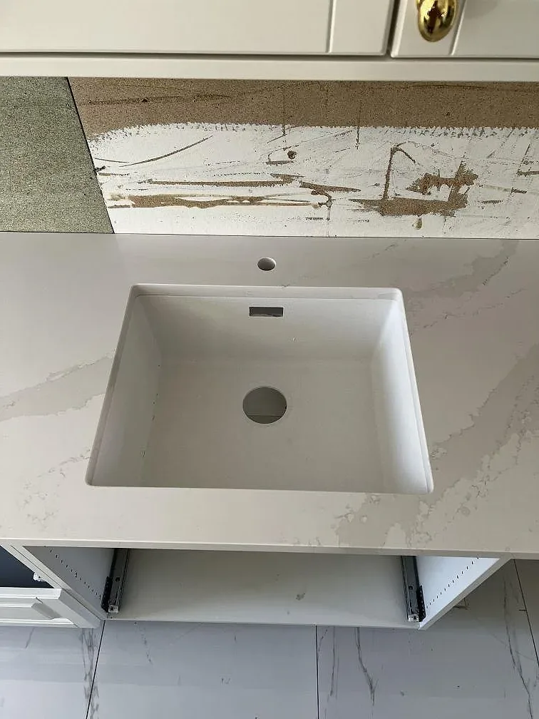 Underlimmad vit komposithoar infälld i en bänkskiva av Silestone Eternal Calacatta Gold i ett kök i Skövde.