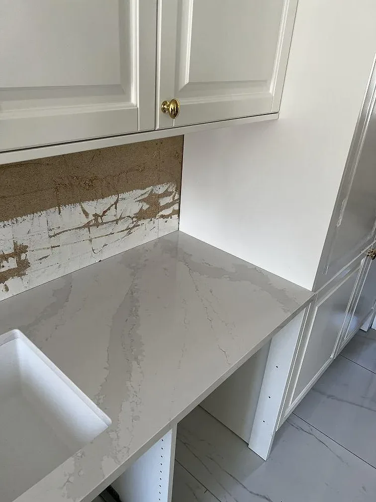 Polerad köksbänkskiva i Silestone Eternal Calacatta Gold med tydlig Calacatta-ådring och underlimmad komposithoar i ett kök i Skövde.