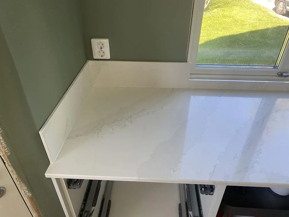 Närbild på den polerade ytan i Silestone Eternal Calacatta Gold med mjuk grå ådring i ett kök i Skövde.