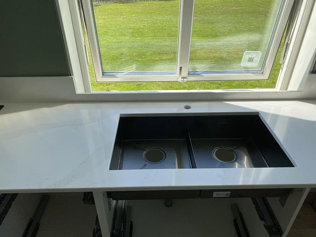 Polerad Silestone Eternal Calacatta Gold köksbänk med uppvikt stänkkant och eluttag mot grön vägg i ett kök i Skövde.