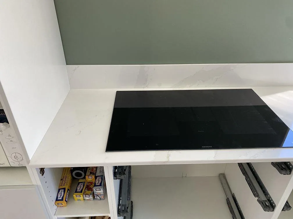 Underlimmad rostfri dubbelho i en polerad köksbänk i Silestone Eternal Calacatta Gold under fönstret i ett kök i Skövde.