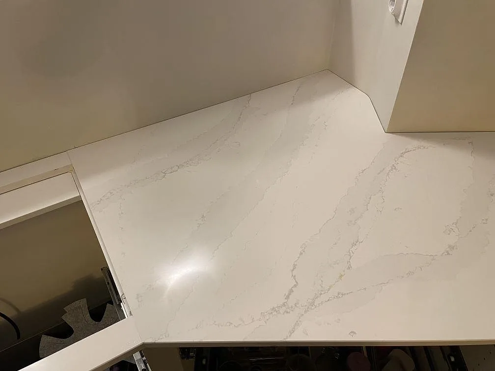Polerad bänkskiva i Silestone Eternal Calacatta Gold med tydlig grå och guldfärgad diagonal ådring, sedd uppifrån i ett kök i Stockholm.
