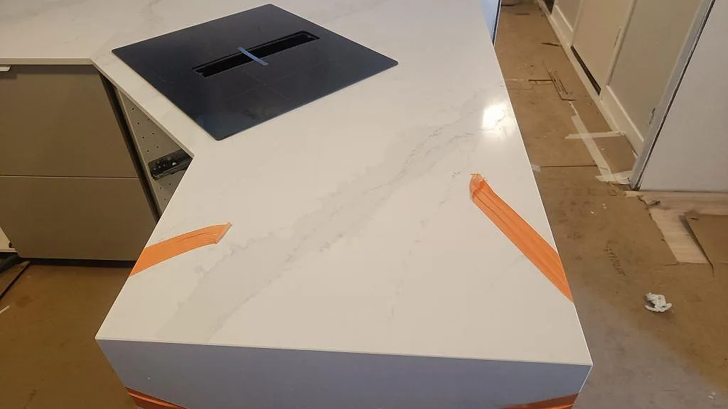 Köksö i polerad Silestone Eternal Calacatta Gold med synlig Calacattaådring och induktionshäll i Vellinge.