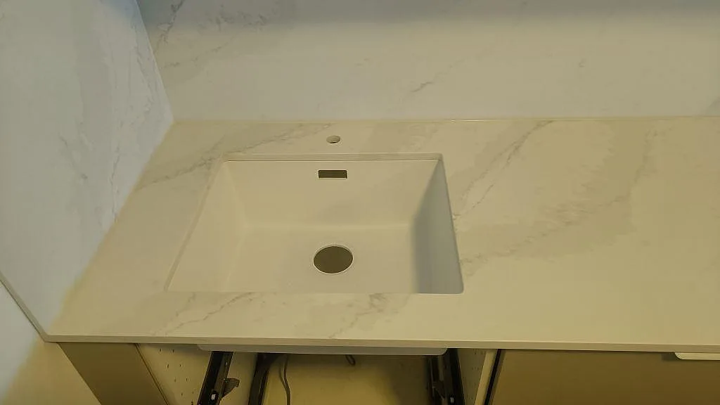 Underlimmad diskho i köksbänkskiva av polerad Silestone Eternal Calacatta Gold med matchande stänkskydd i Vellinge.