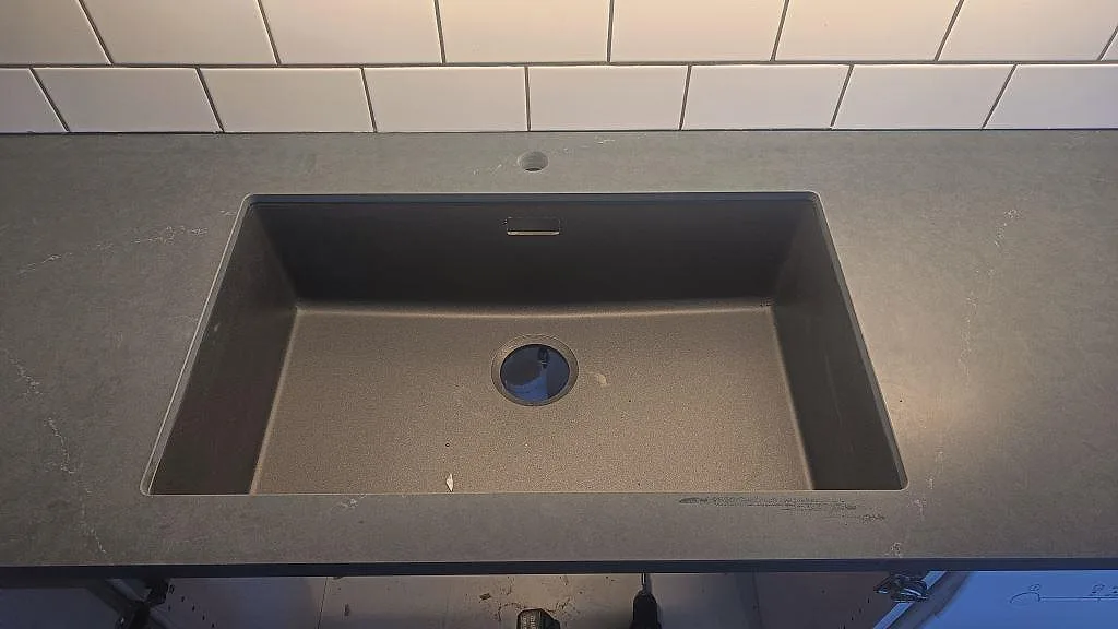 Närbild på svart diskho under bänkskiva i Silestone Eternal Charcoal Soapstone, matt kompositsten, i ett kök i Göteborg.