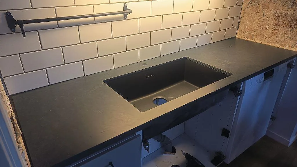 Köksbänkskiva i Silestone Eternal Charcoal Soapstone, matt Mocka-finish, med svart underlimmad diskho och vitt subway-kakel i Göteborg.