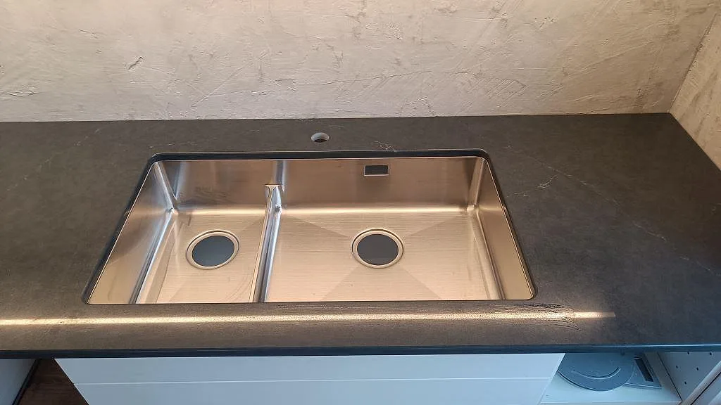 Underlimmad dubbelho i rostfritt stål monterad i en polerad Silestone Eternal Charcoal Soapstone bänkskiva i Södra Sandby.