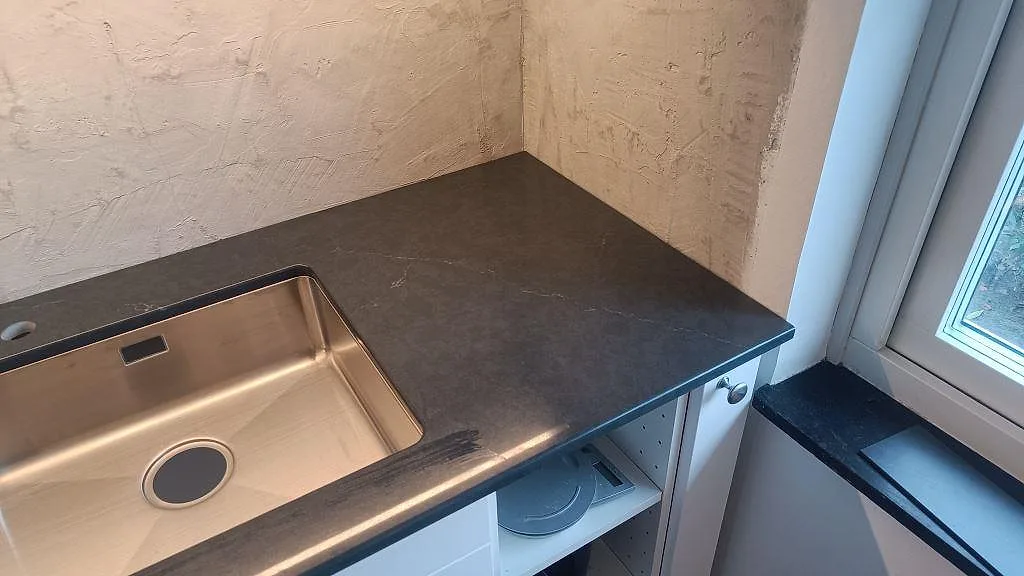Fönstersidan av köket med polerad Silestone Eternal Charcoal Soapstone och underlimmad rostfri diskho i Södra Sandby.