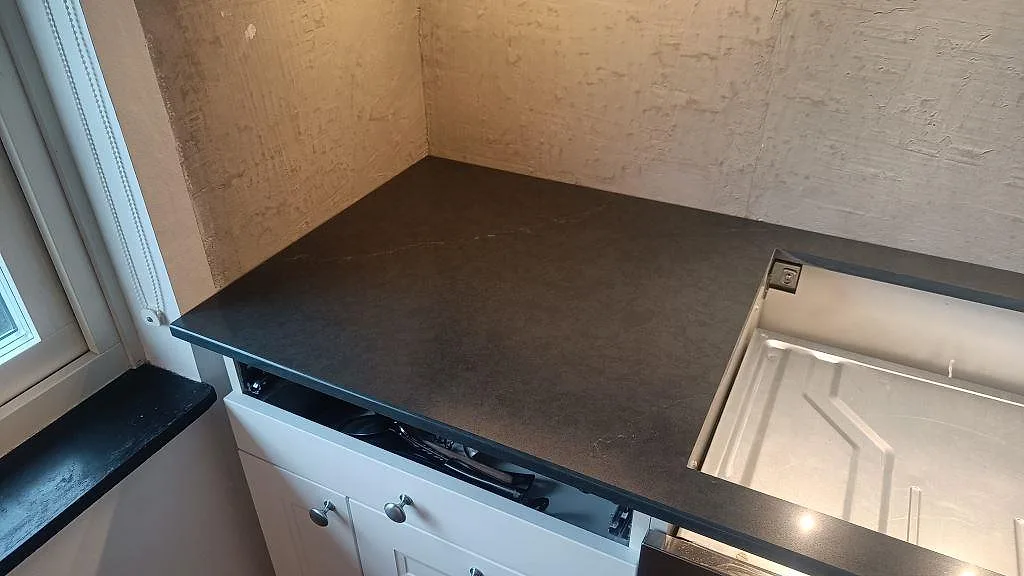 Mörk polerad kompositbänkskiva i Silestone Eternal Charcoal Soapstone vid köksfönstret i Södra Sandby.