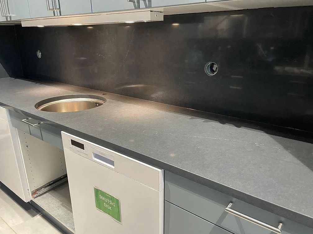 Närbild av polerad Silestone Eternal Charcoal Soapstone som köksbänkskiva med rund rostfri diskho och mörkt stänkskydd i Trollhättan.