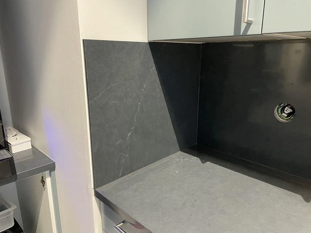 Sidovy av polerad Silestone Eternal Charcoal Soapstone med 12 mm mörkt stänkskydd, vägguttag och grå köksinredning i Trollhättan.