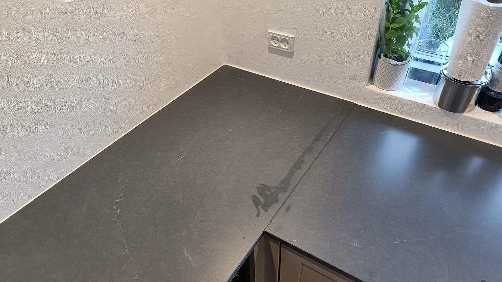 Hörn av matt grå Silestone Eternal Charcoal Soapstone bänkskiva med diskret vit ådring och fönsterbänk i ett kök i Vedbæk.