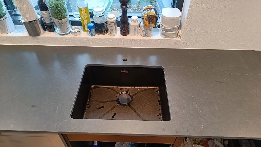 Underlimmad svart kompositdiskho i en matt antracitgrå Silestone Eternal Charcoal Soapstone bänkskiva i Vedbæk.
