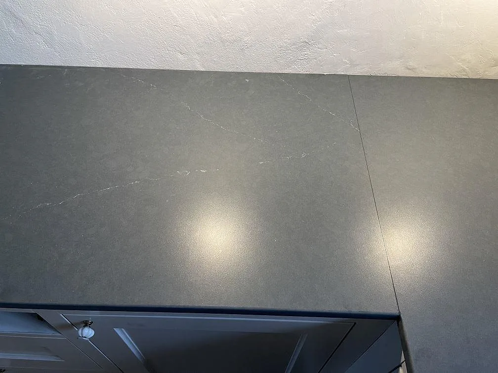 Köksbänkskiva i mörkgrå Silestone Eternal Charcoal Soapstone, matt yta med mjuk vit ådring, sedd ovanifrån över köksskåpen i Vintrie.