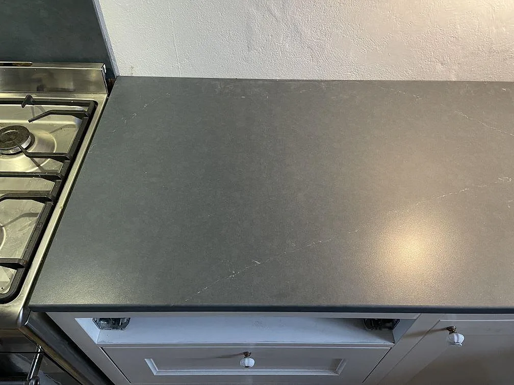 Köksbänkskiva i Silestone Eternal Charcoal Soapstone, matt mörkgrå kvartskomposit med vit ådring, monterad intill en fristående rostfri spis i ett kök i Vintrie.