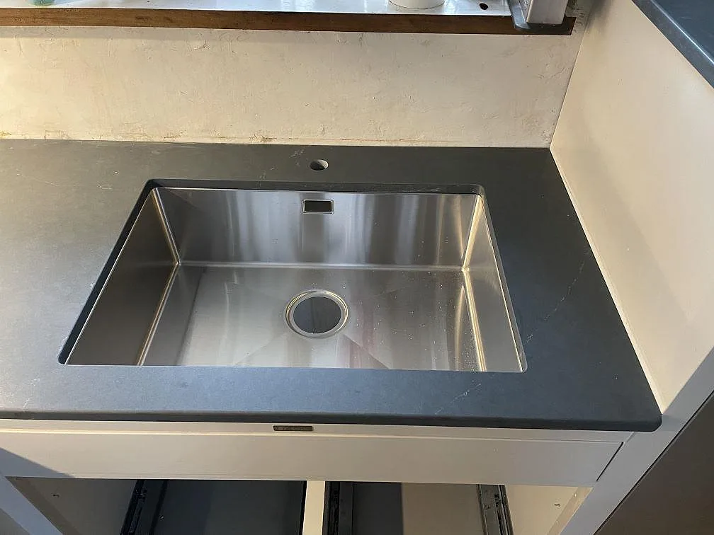 Underlimmad rostfri diskho i en köksbänkskiva av Silestone Eternal Charcoal Soapstone, matt mörkgrå komposit, i ett kök i Vintrie.