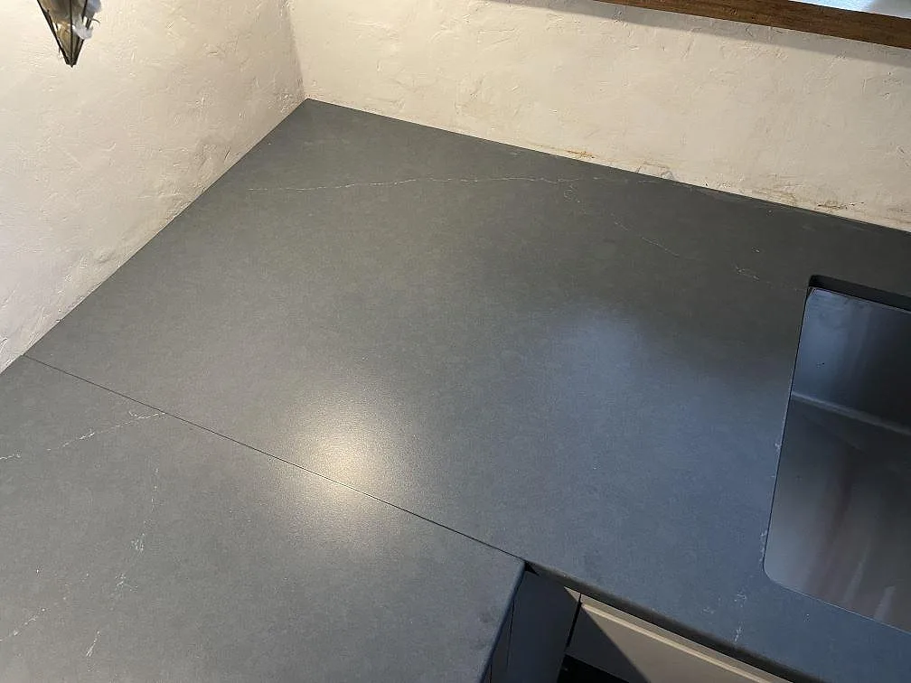 Hörnparti av köksbänkskiva i Silestone Eternal Charcoal Soapstone, matt charcoalgrå komposit med diskhopartiet synligt, i ett kök i Vintrie.