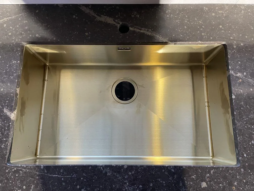 Stor underlimmad diskho i guldtonat rostfritt stål i bänkskiva av brun Silestone Eternal Emperador i Urshult.