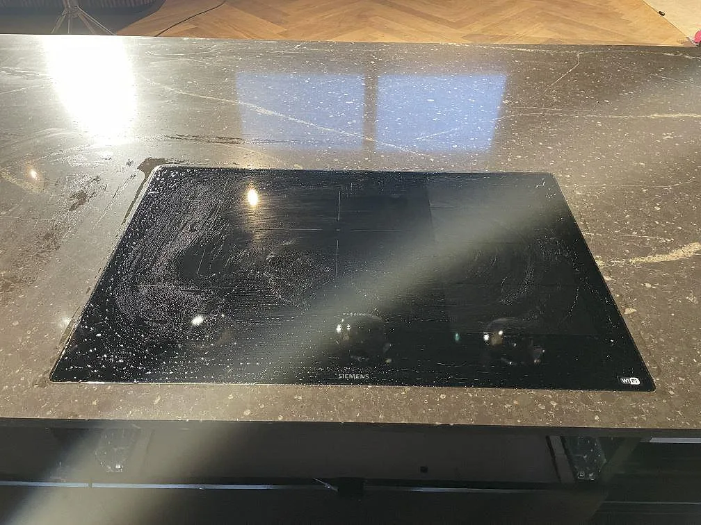 Polerad köksö och väggbänk i mörkbrun Silestone Eternal Emperador med ljus ådring i ett kök under montering i Urshult.