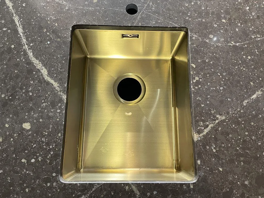 Underlimmad mässingsfärgad diskho i polerad Silestone Eternal Emperador med blandarhål och ljus ådring i Urshult.