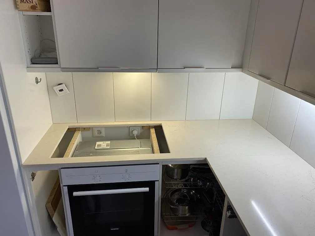 Polerad köksbänkskiva i Silestone Eternal Marfil med utskuren hällöppning och ljus vägg i Lomma.