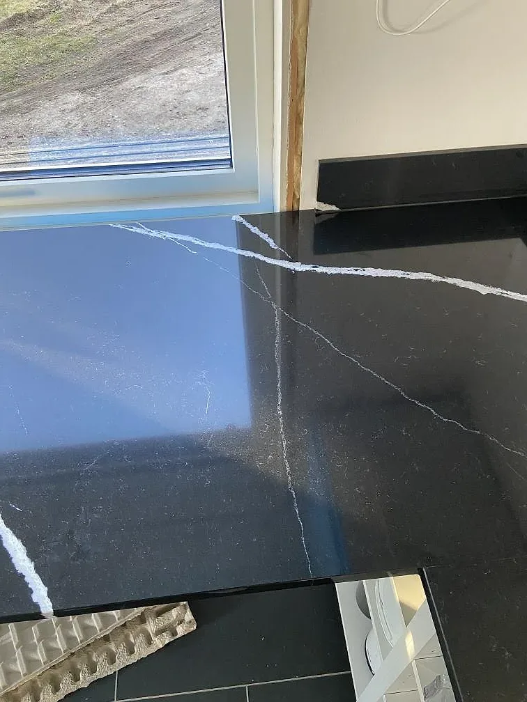 Polerad svart Silestone Eternal Marquina köksbänkskiva med markerad vit ådring intill fönster i ett kök i Eslöv.