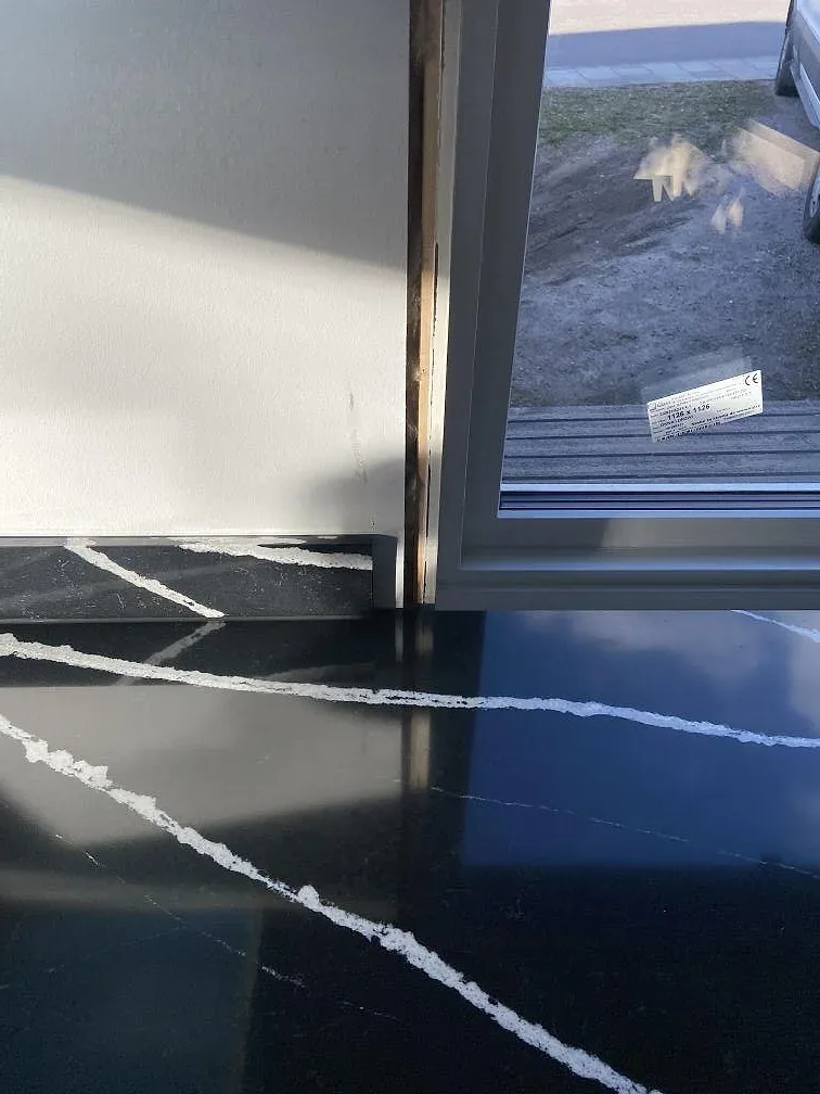 Polerad svart Silestone Eternal Marquina köksbänkskiva med vit ådring mot fönster och ljus vägg i ett kök i Eslöv.