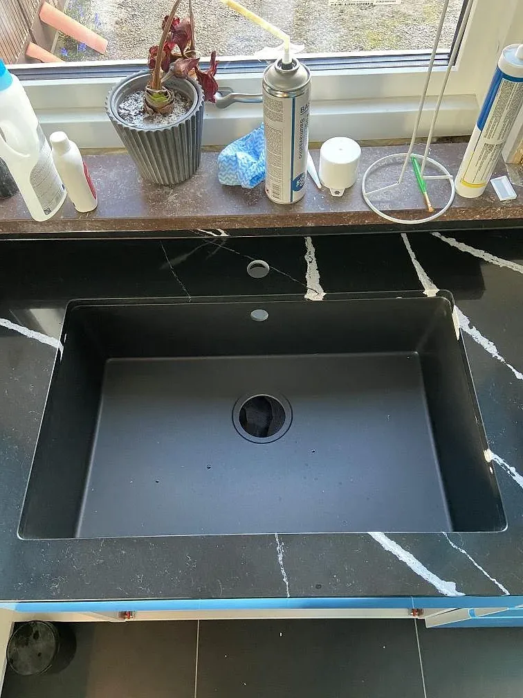 Underlimmad komposithoar i antracit nedsänkt i polerad svart Silestone Eternal Marquina med vit ådring, köksbänkskiva i ett kök i Eslöv.