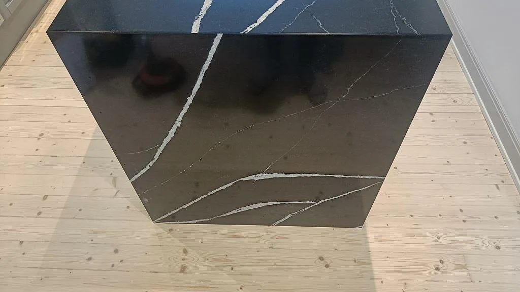 Sidan av köksön i polerad Silestone Eternal Marquina med markant vit ådring mot trägolv i Malmö.
