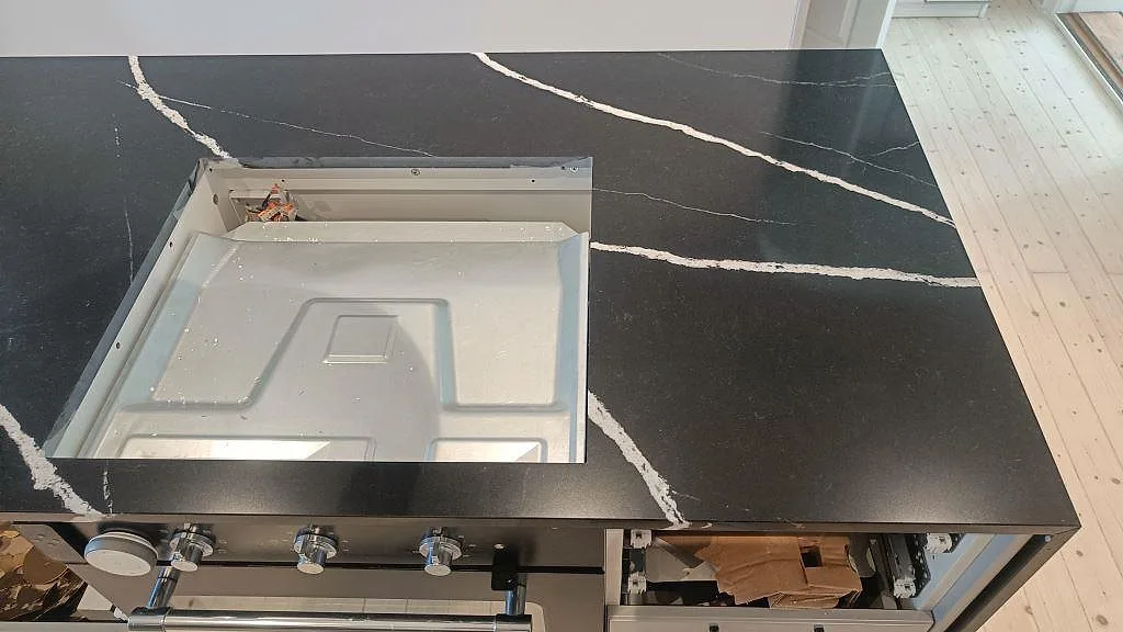 Köksö i Silestone Eternal Marquina med urtag för häll, polerad svart yta med vit ådring, i ett kök i Malmö.