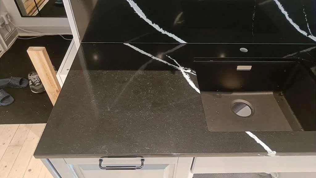 Väggbänk i Silestone Eternal Marquina med urtag för diskho och hög stänkvägg i samma sten i ett kök i Malmö.