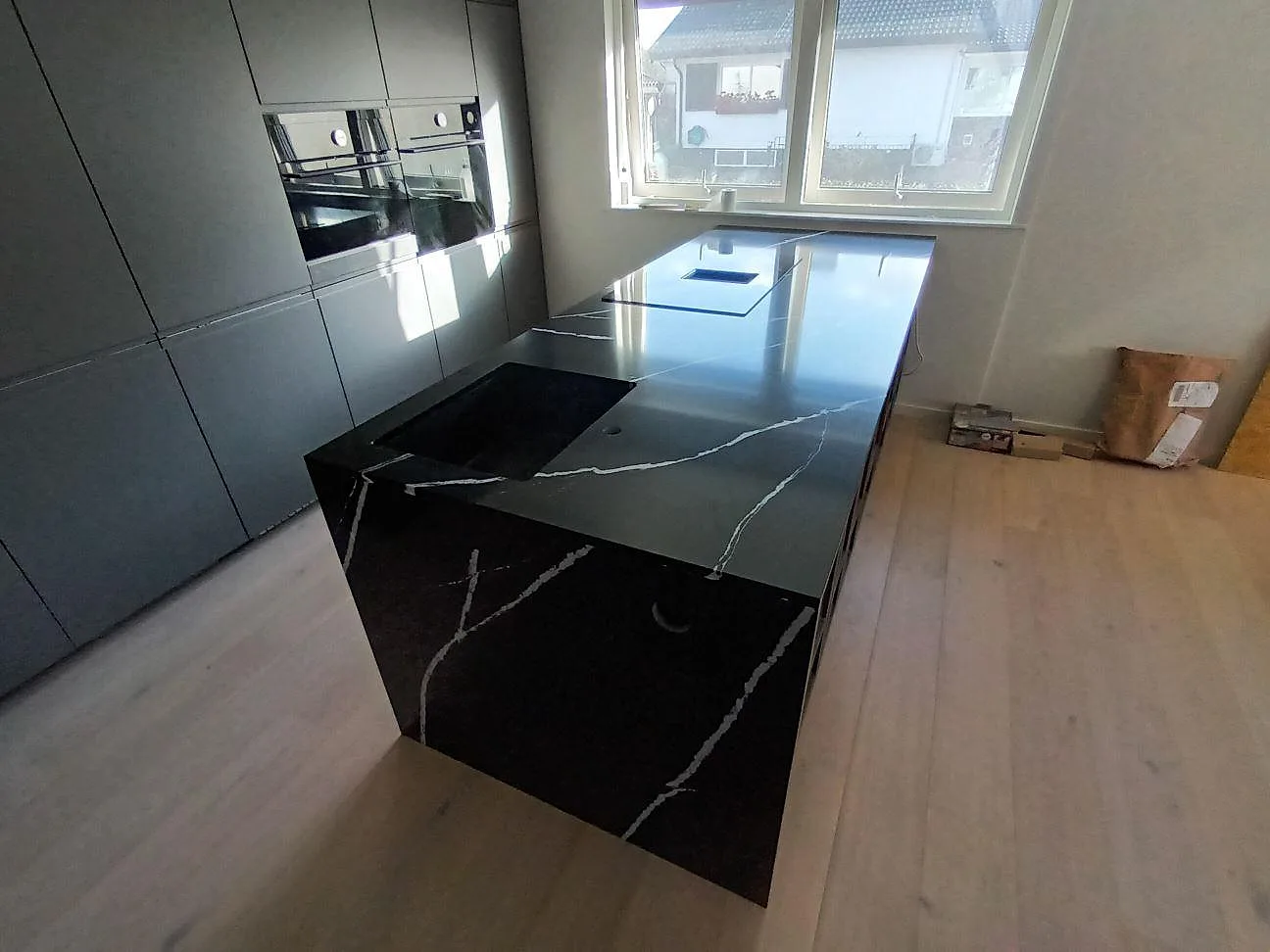 Köksö i svart Silestone Eternal Marquina, polerad komposit med vit ådring och stengavel i ett kök i Norrköping.