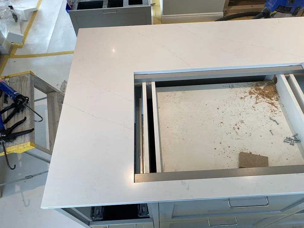 Köksö i polerad Silestone Eternal Statuario med utskuren plats för häll i ett kök i Åryd.
