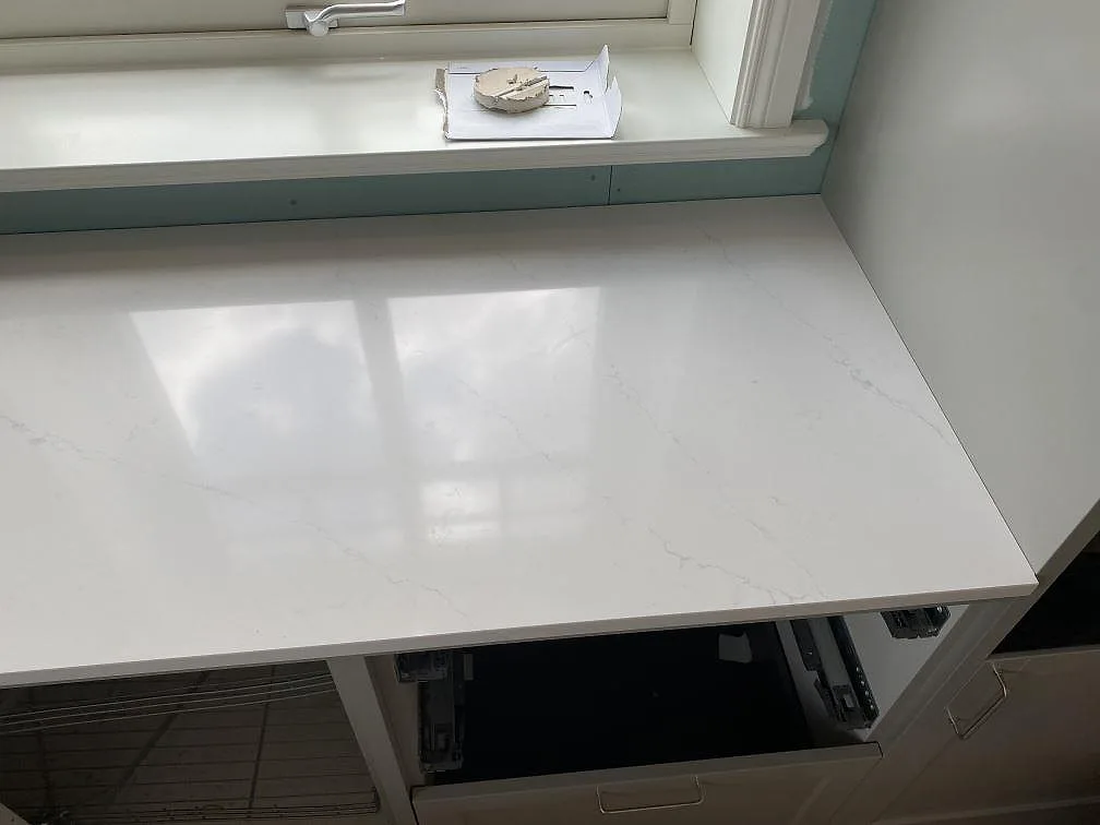 Helbild av ett kök under montering med köksö i polerad Silestone Eternal Statuario och utskuren plats för häll i Åryd.