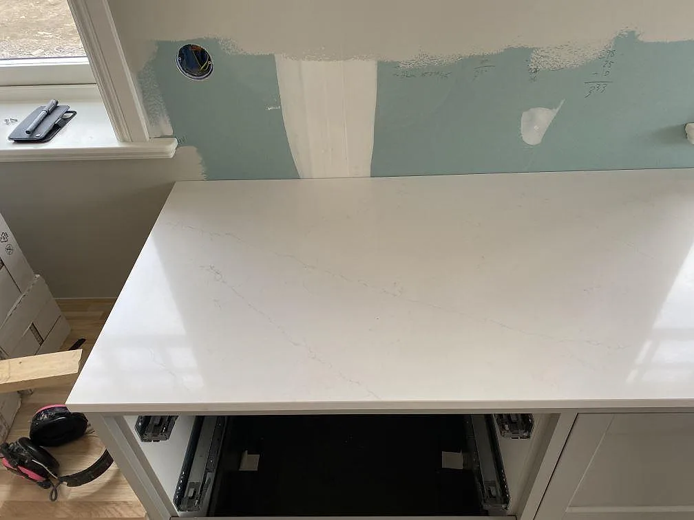 Köksbänkskiva i vit Silestone Eternal Statuario, polerad, monterad mot fönsterläge i ett kök under inredning i Åryd.