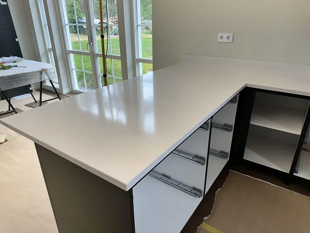 Kökshalvö i polerad Silestone Eternal Statuario med vit kvartskomposit och diskret grå ådring under montering i Åsa.