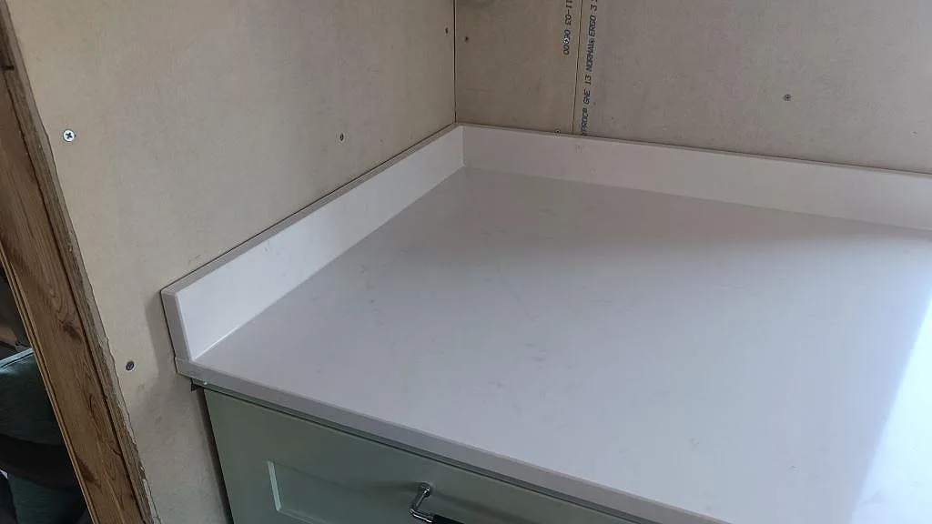 Närbild på polerad Silestone Eternal Statuario med uppvikt stänkkant och grön köksinredning i Alingsås.