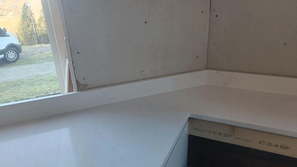 Köksdetalj i Silestone Eternal Statuario med polerad yta, hälluttag och stänkkant vid fönster i Alingsås.